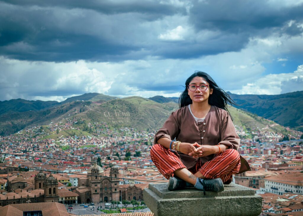 pexels-photo-29853302-29853302 A woman sits on a rooftop with a stunning view of Cusco, Peru's historic landscape.